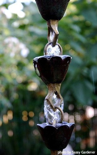 Black acorn style acorn water cups with Radisson diamond bottoms with water flowing over top, garden water art, feng shui water feature,rain gardens, gardening bliss, chains hoses, rain barrels, chain fountain.