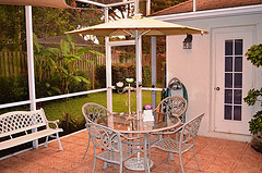 Metal outdoor furniture, white outdoor furniture set with umbrella on deck with palm trees.