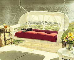 Outdoor Wicker garden furniture, white resin wicker swing chair in front of waterfront.