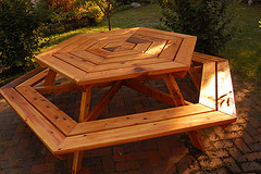  Red Cedar Outdoor Furniture, hexagon Cedar picnic table on brick patio.