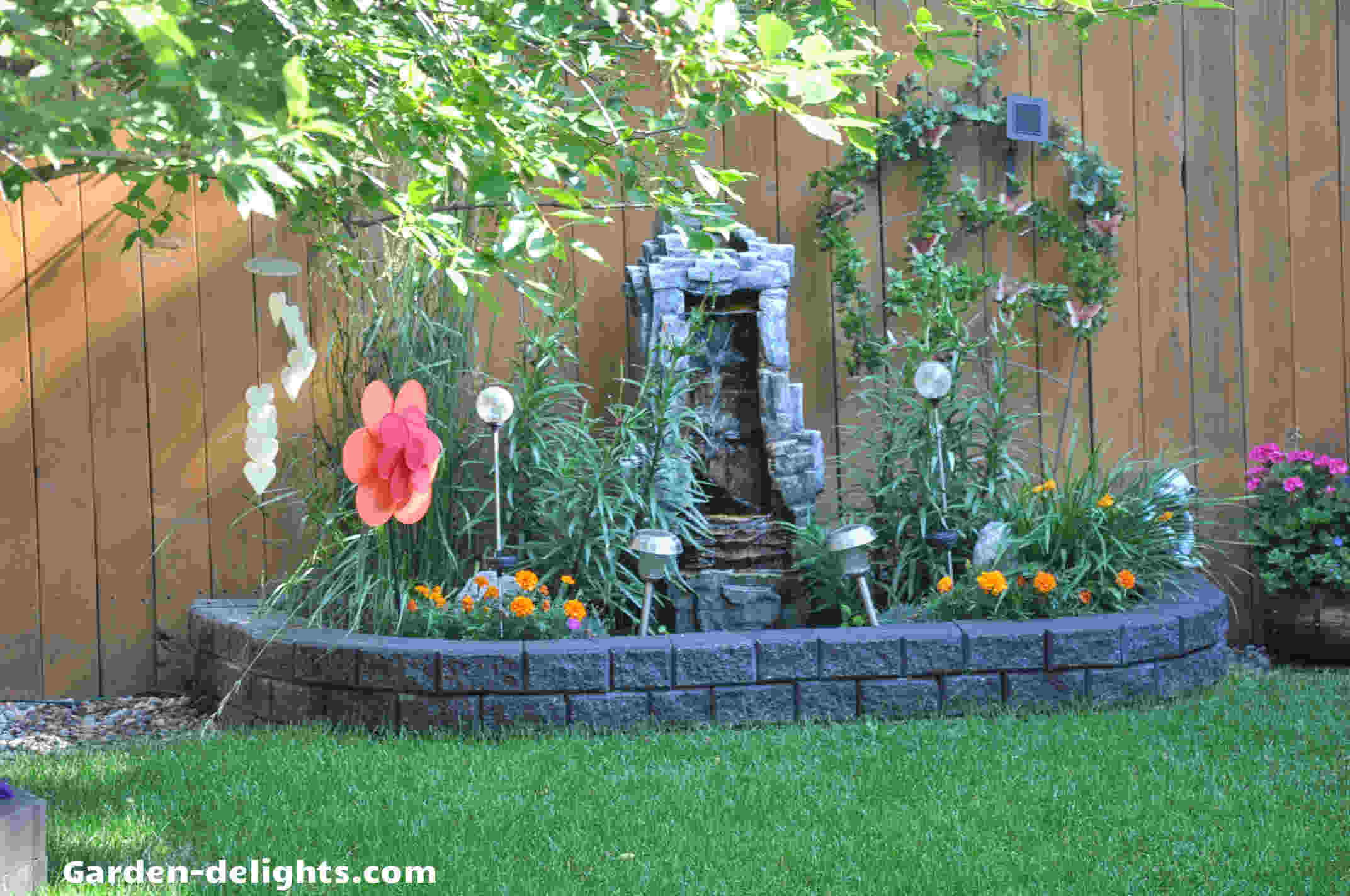  Stonewall water feature in flower bed surrounded by red tulips against Cedar fence, water fountain, Home Depot, large outdoor fountains, landscaping ideas, backyard planning, patios,Gardening insights, modern fountain, sleek fountain, water fountain ideas, garden water feature, small water features.