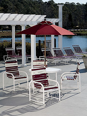Discounted Outdoor Furniture, aluminum frame with plastic wrap red and white striped chairs with aluminum table and glass top and red umbrella.