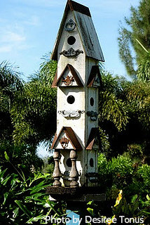 
Tall white wooden birdhouse tower with tall roof peak and multiple bird hole entrances with front porch. Wooden birdhouses, decorative wood birdhouses