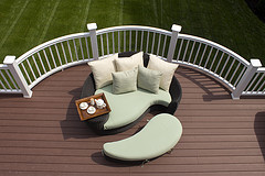 Outdoor Furniture Cushions, tear shaped loveseat and footstool with green and white patio cushions on deck overlooking backyard.