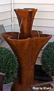 Unique terra-cotta resin fountain with waterspouts pouring water into second-tier four leaf clover shape mounted with round basin bottom, decorative corner water fountain, unique water fountain.