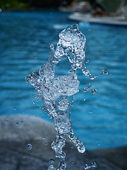 Water droplets suspended in the air with garden pond behind, small waterfalls, majestic water fountains.