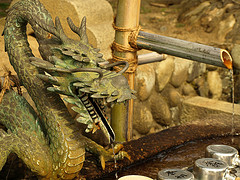 Dragon head reaching out into the water with a curled up body behind with most open and water pouring out into the Japanese water pond.Japanese water fountains, Japanese garden fountains,Japanese fountain with Dragon.