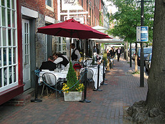 Outdoor Cafe Furniture, restaurant Café furniture with red umbrella and waiter on street in front of Café.