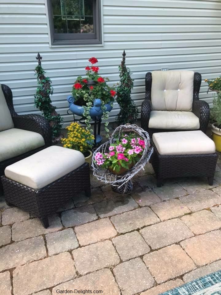 Wicker patio chairs with Ottomans with light brown cushions on Brick stone patio, outdoor backyard, types of patio furniture, material for patio furniture.