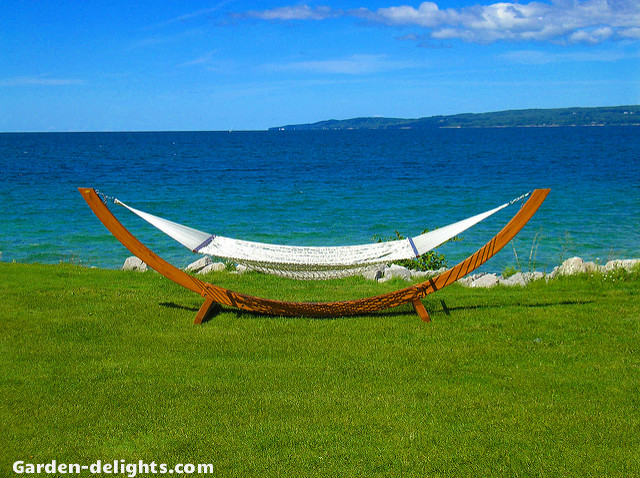  Wooden bow shape hammock stand with white rope cotton on beach in front of ocean. Hammocks backyard, hammock swings, hammock ideas, outdoor hammock, Home Depot, portable hammock stands, hammocks stand kit